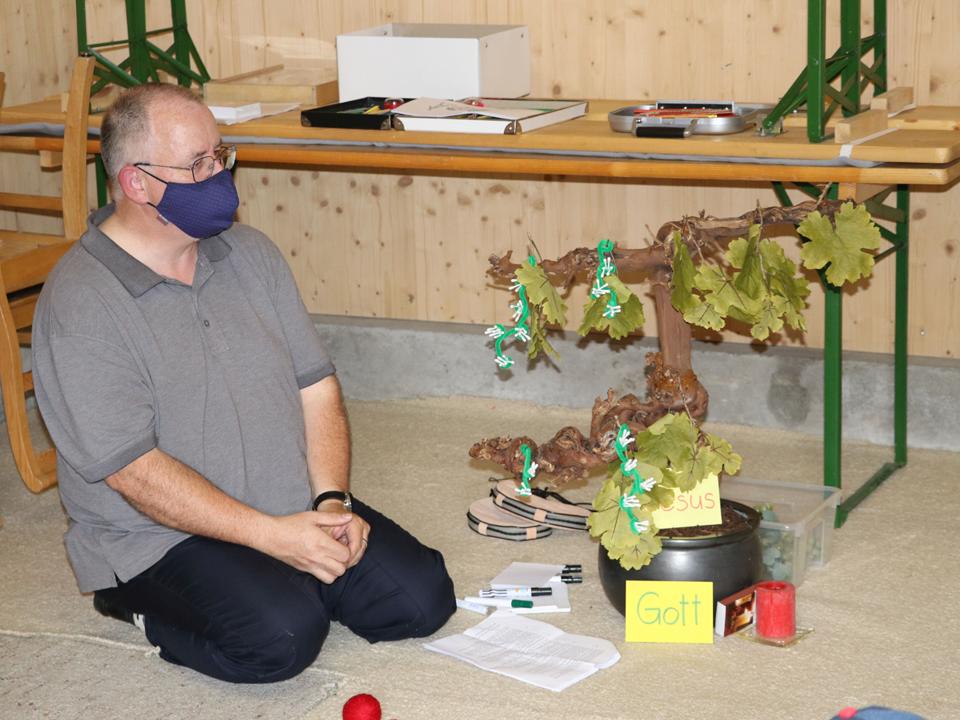 Norbert Schalk bringt Blätter und Trauben an den Weinstock an, der sinnbildlich für Jesus steht.