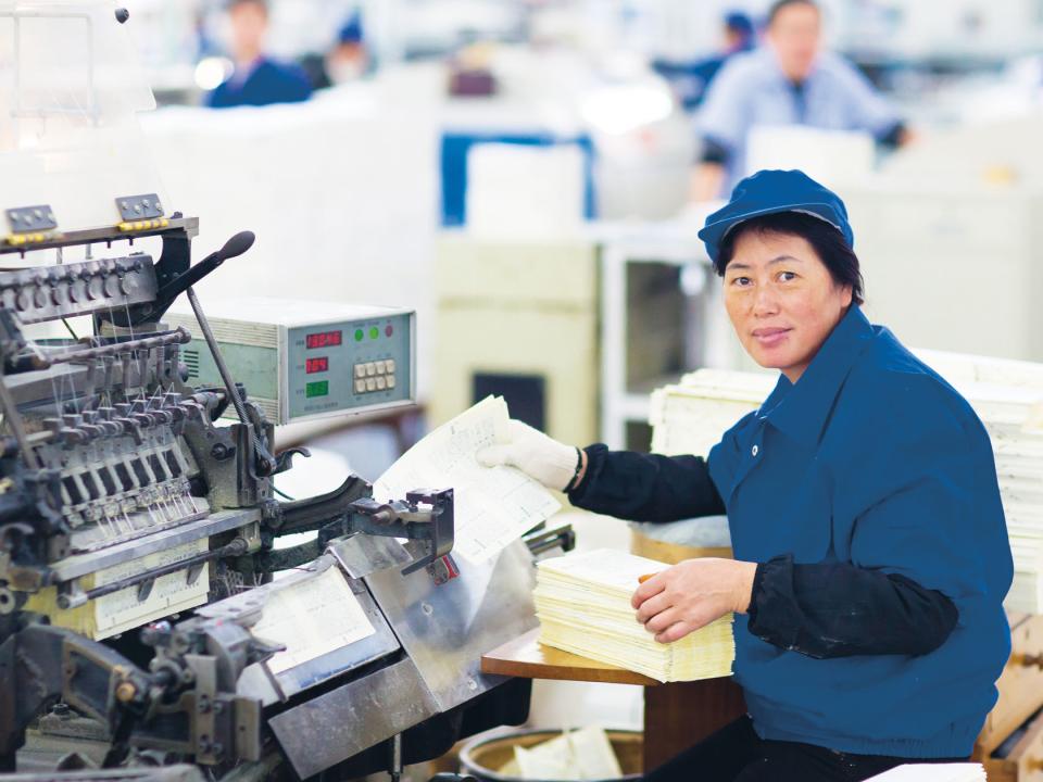 Chinesische Druckereimitarbeiterin an einer Maschine