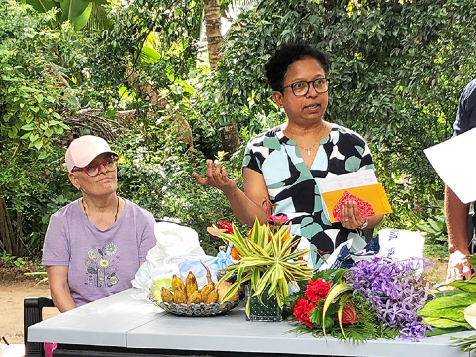 eine Vorstandsfrau vom Verein Lankawelamai sitzend, Co-Präsidentin Yulanie Perumbadage stehend mit Couvert für Patenkinder in Sri Lanka