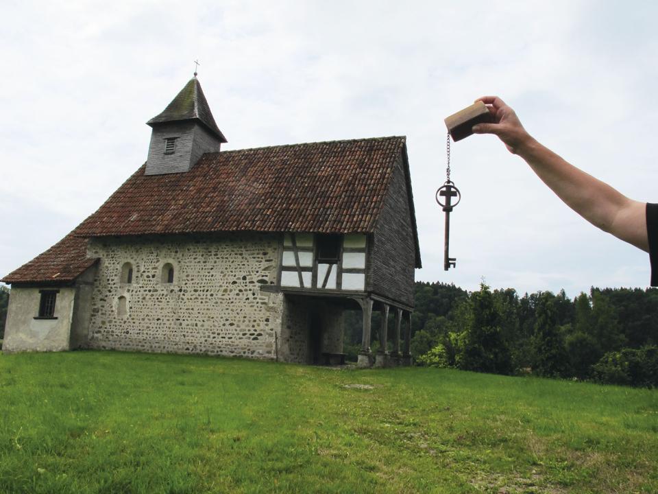Schlüssel wird vor Kamera gehalten für Kapelle Degenau daneben