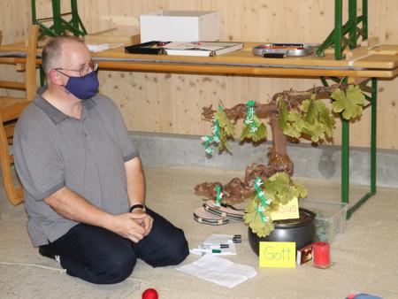 Norbert Schalk bringt Blätter und Trauben an den Weinstock an, der sinnbildlich für Jesus steht.