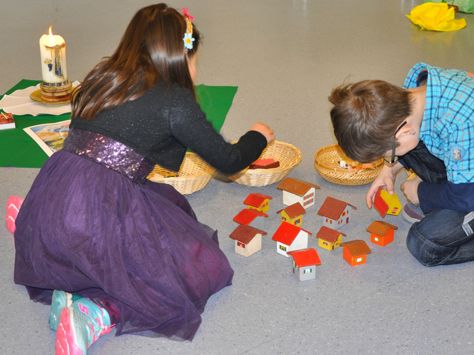 Zwei Kinder spielen mit Holzhäuschen das Gehörte in der «Chinderfiir» nach.