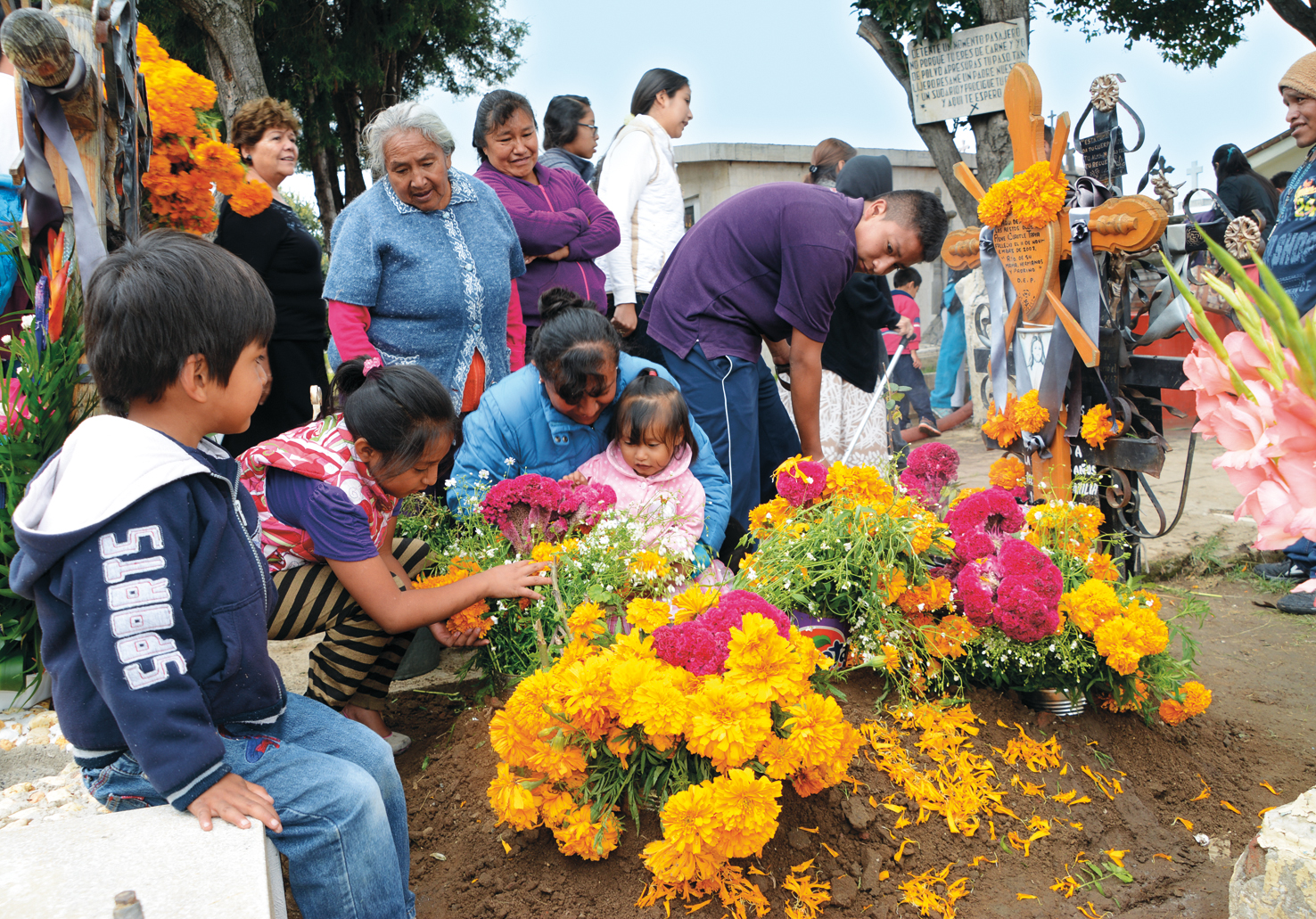 Familie schmückt ein Grab am « Día de los Muertos »