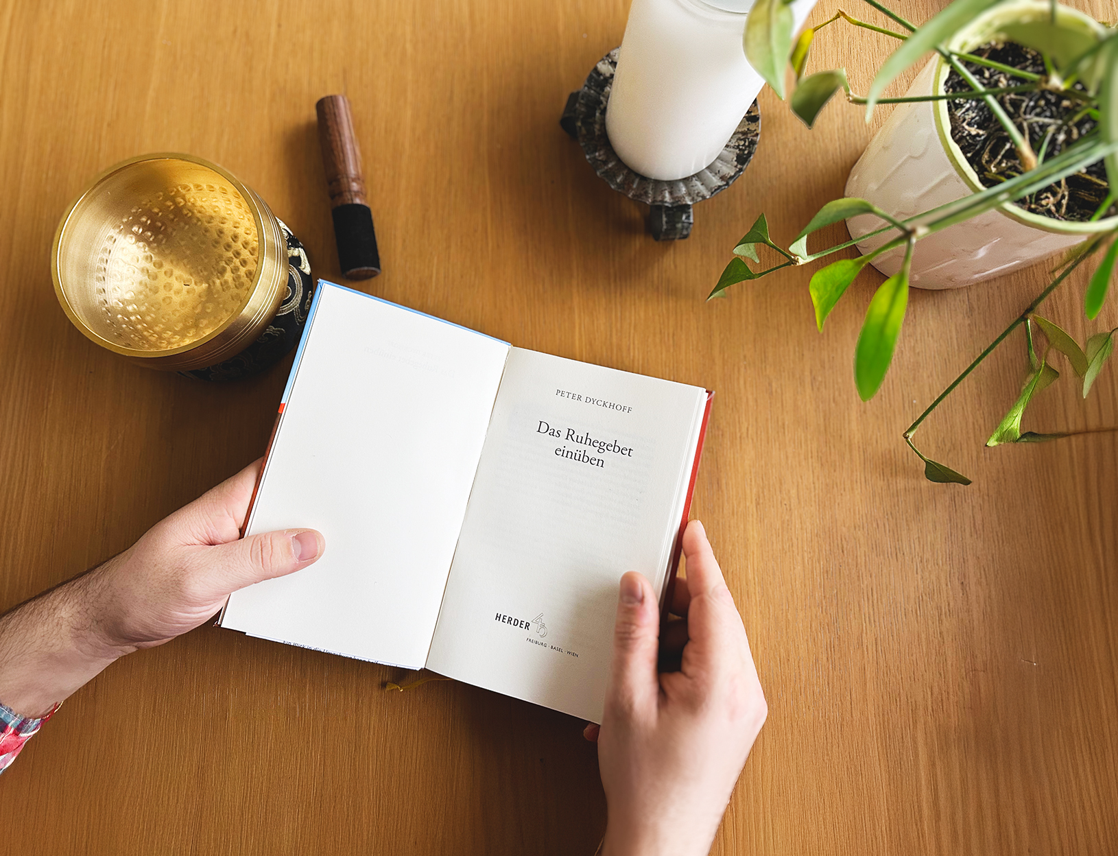 Hände halten ein Buch, daneben eine Klangschale